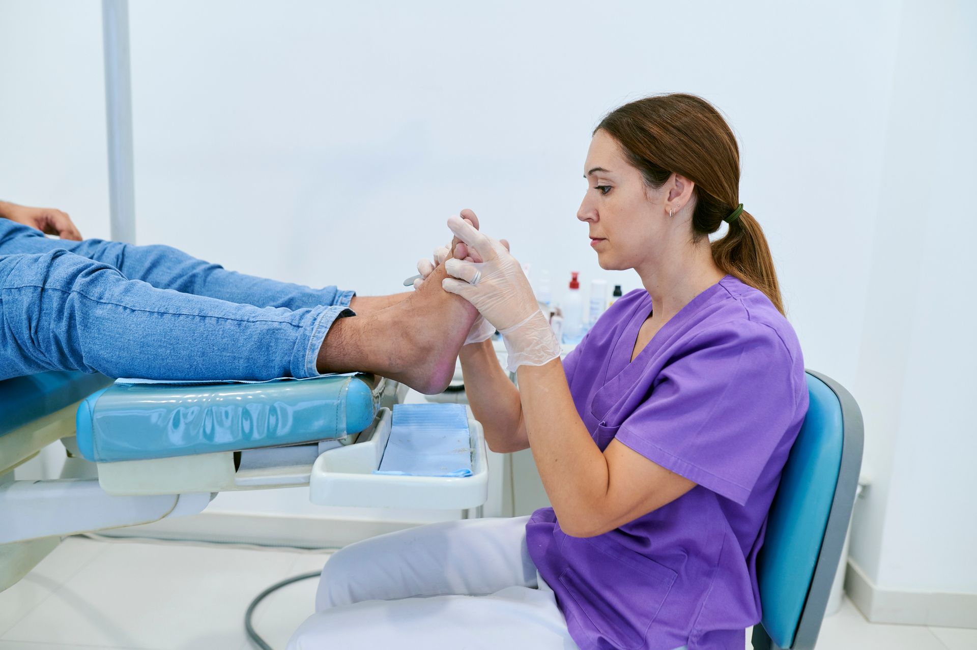 A woman is inspecting a patient’s feet.
