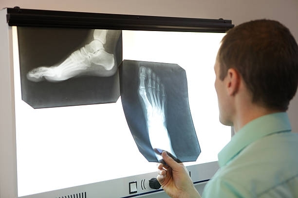 A doctor is examining a patient’s foot X-ray.