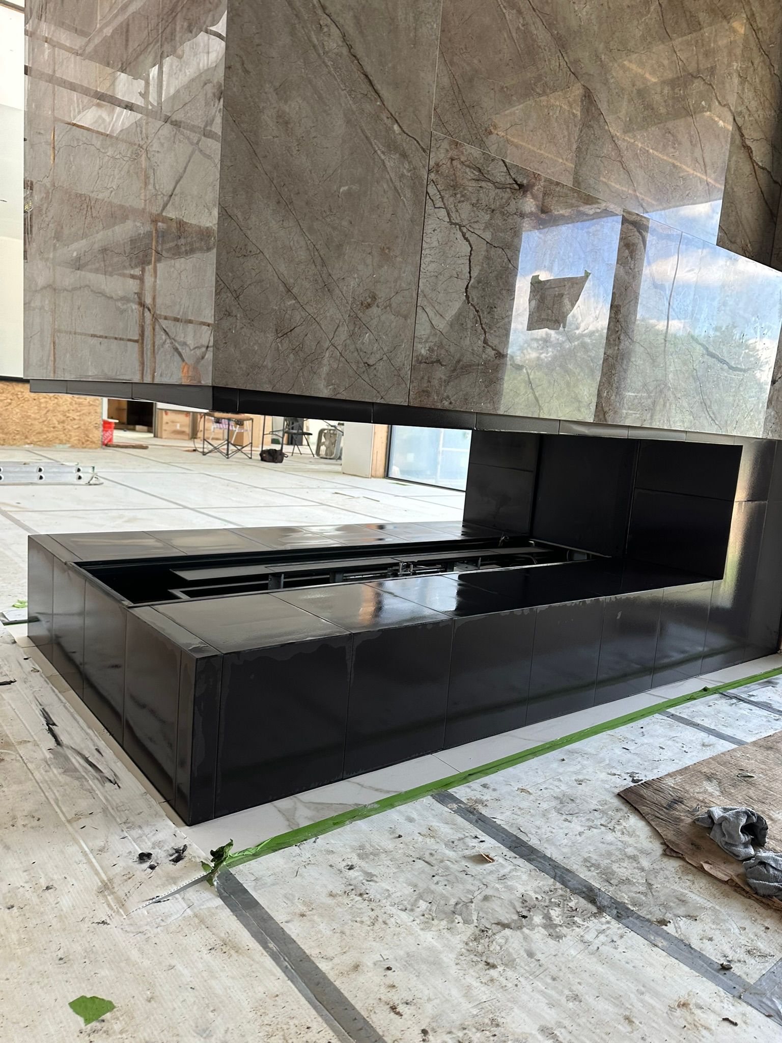 Modern architectural design with dark gray and black stone. Reflective surfaces in a workshop setting.