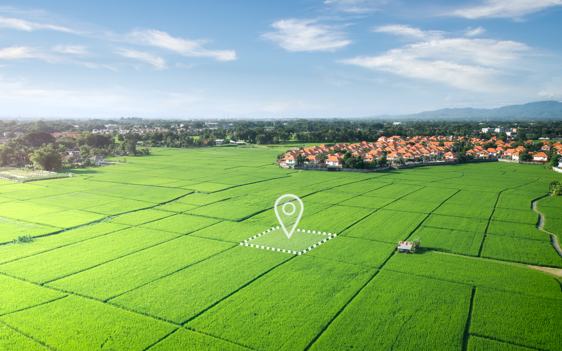 An aerial view of a lush green field with a pin pointing to a location.