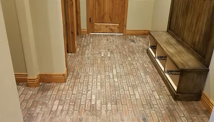A hallway with a brick floor and a wooden bench.