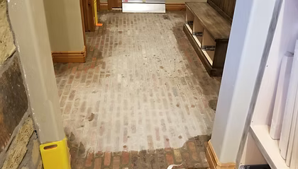 A hallway with a brick floor and a wooden bench.
