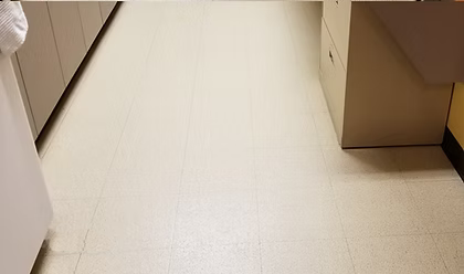 A white tile floor in a kitchen with a desk and cabinets.