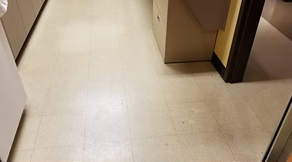 A white tiled floor in a room with a filing cabinet.