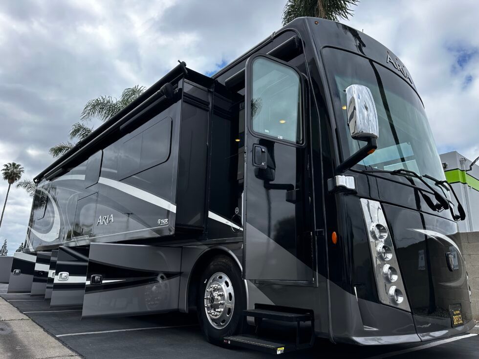 A large black rv is parked in a parking lot.