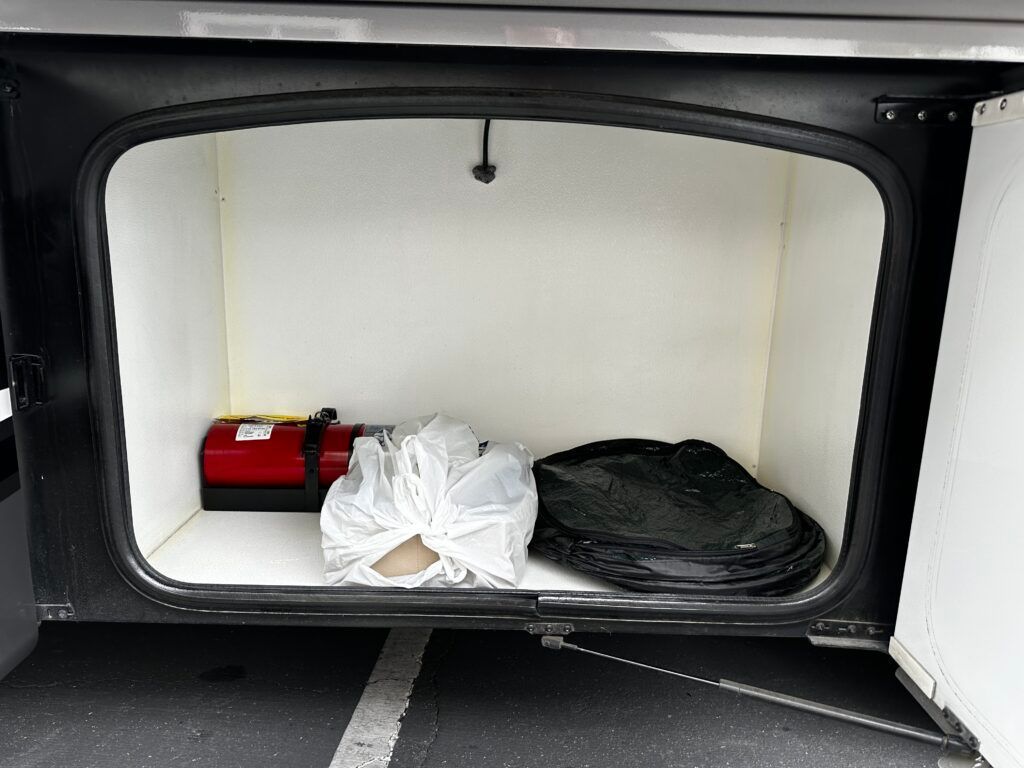 The trunk of a car with a bag and a fire extinguisher in it
