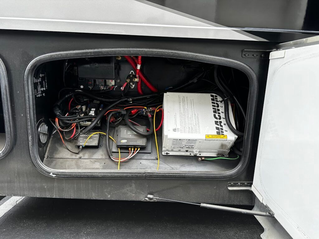 The inside of a rv with the door open and a battery in it.