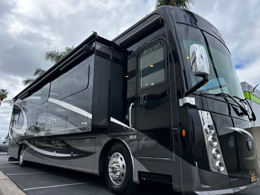 A large black rv is parked in a parking lot.
