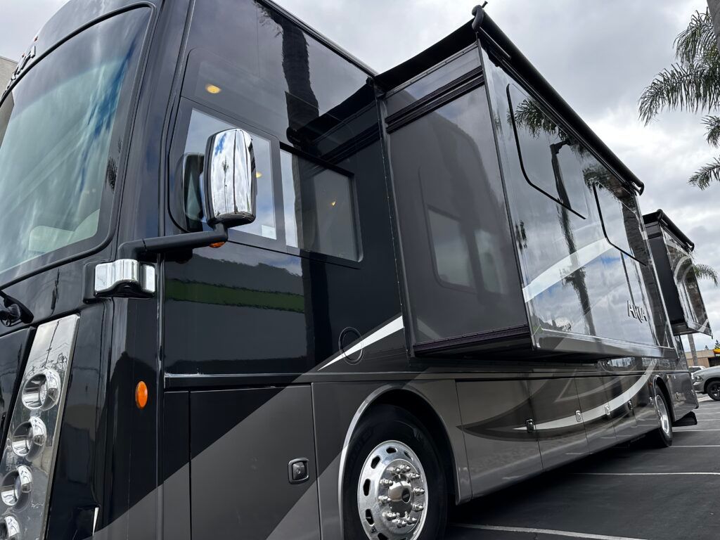 A large black rv is parked in a parking lot.