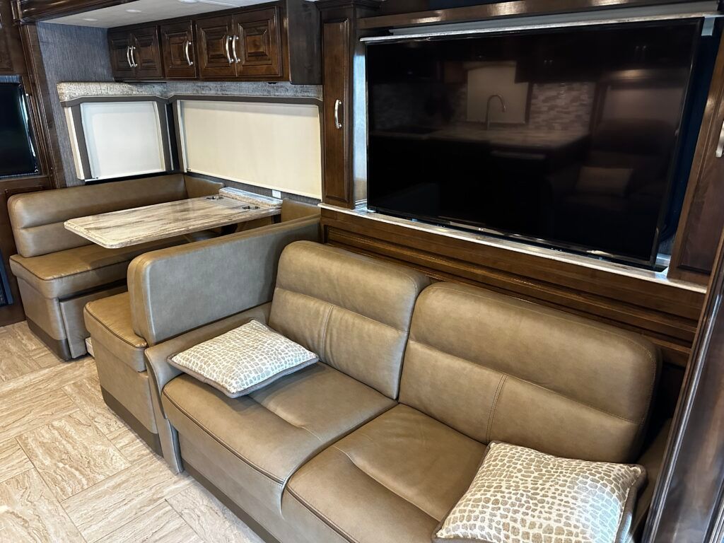 A living room in a rv with a couch , table and television.