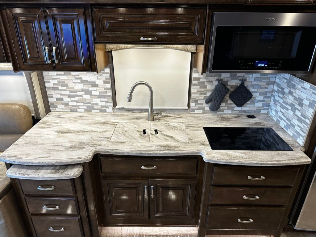 A kitchen with a sink , stove and microwave.
