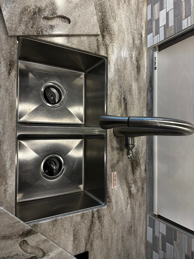 A kitchen sink with two stainless steel sinks and a faucet.