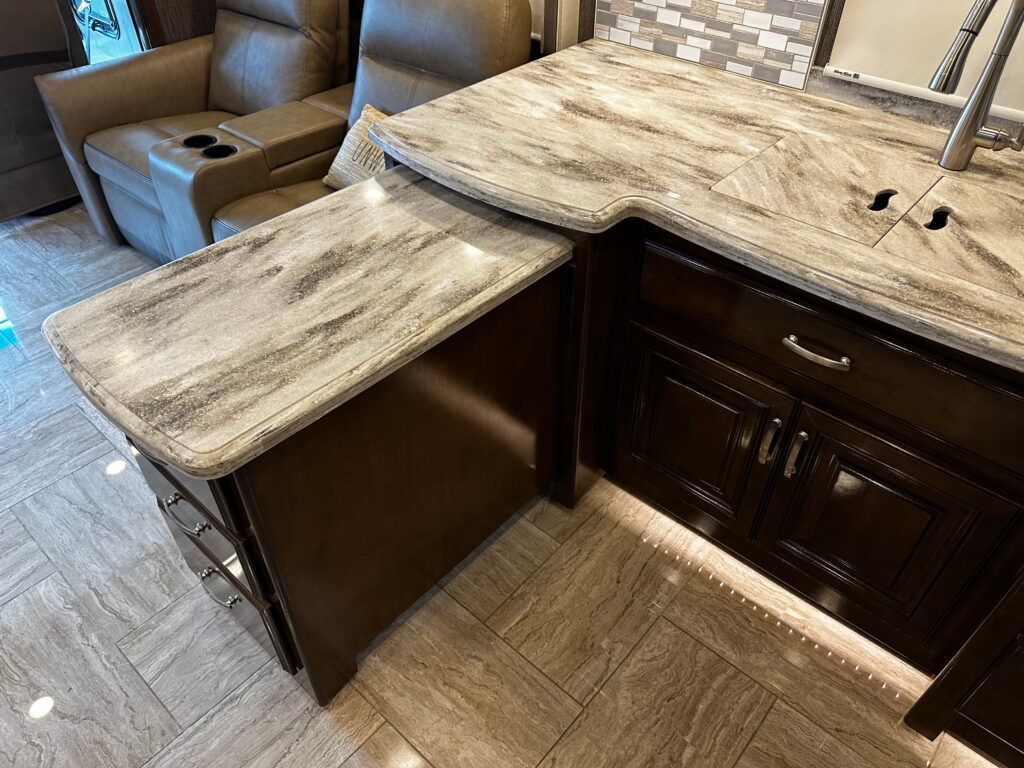 A kitchen with a granite counter top , cabinets , and a chair.