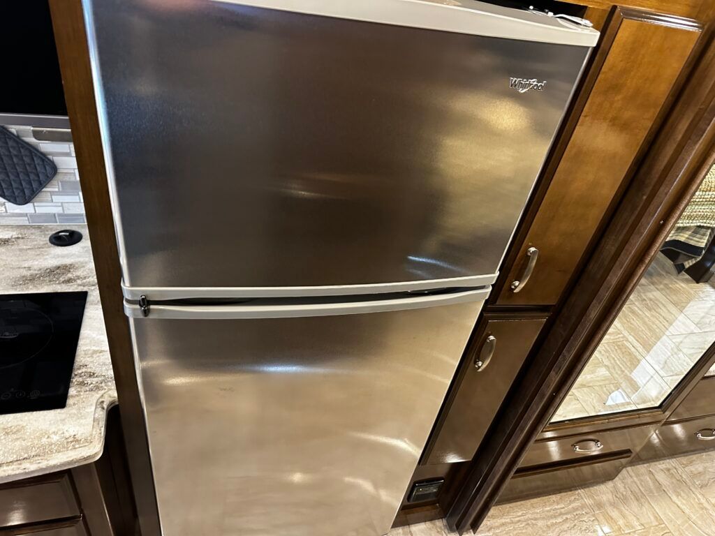 A stainless steel refrigerator is sitting in a kitchen next to a stove.