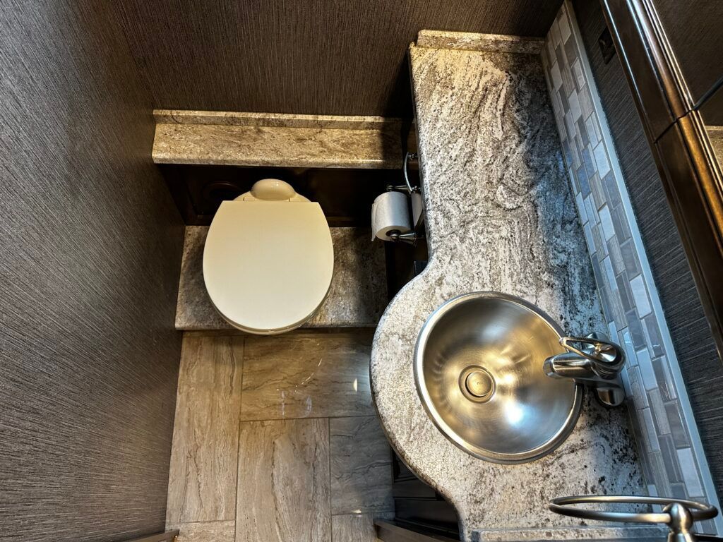 A bathroom with a toilet , sink and mirror.