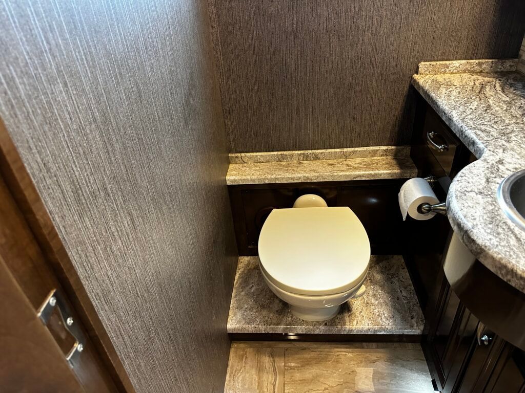 A bathroom with a toilet , sink and toilet paper.