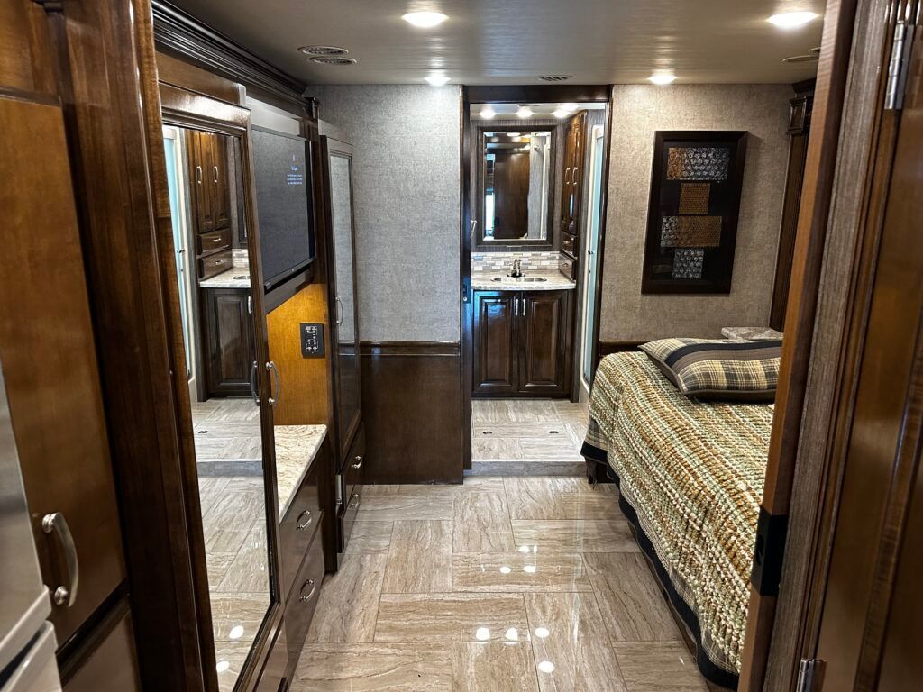 A bedroom with a bed and a bathroom in a rv.