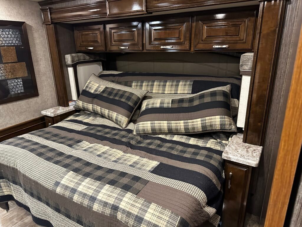 A bed with a striped comforter and pillows in a rv.