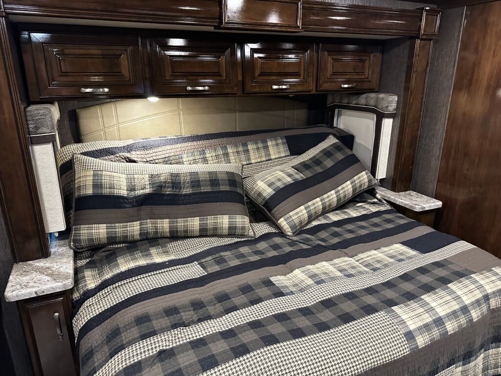 A bed with a plaid comforter and pillows in a rv.