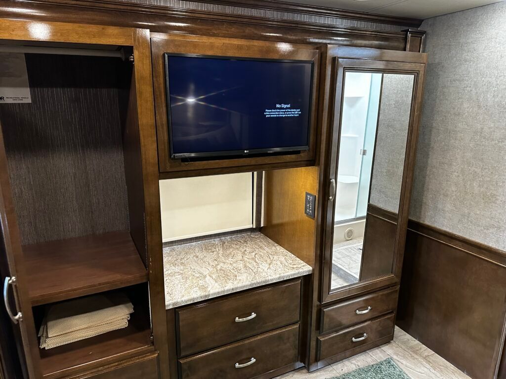 A closet with a flat screen tv on top of it.