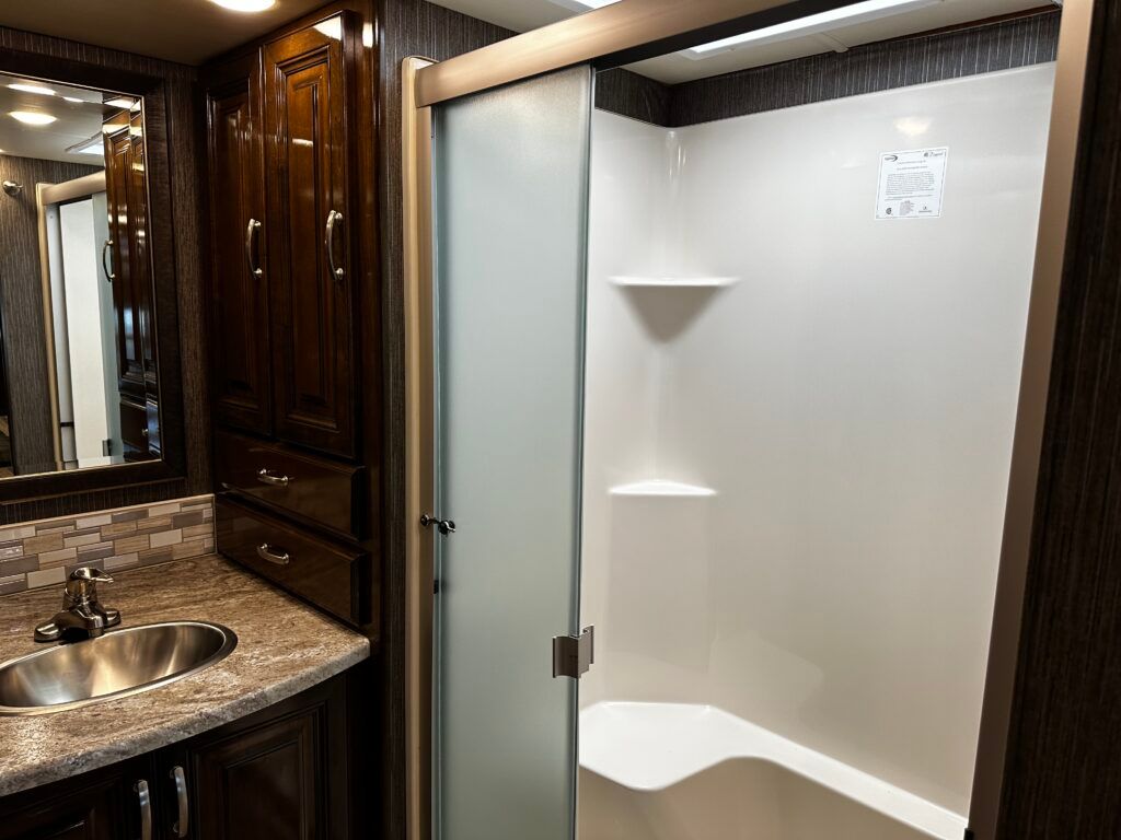 A bathroom with a sink , mirror and shower.