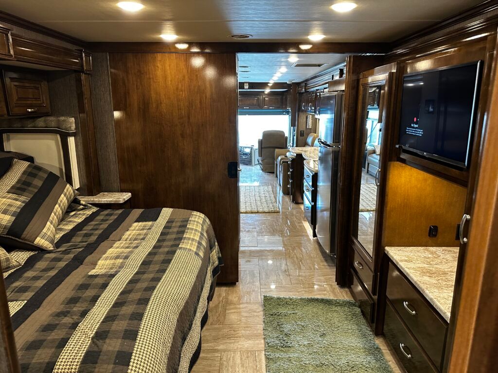 A bedroom in a rv with a bed and a television.