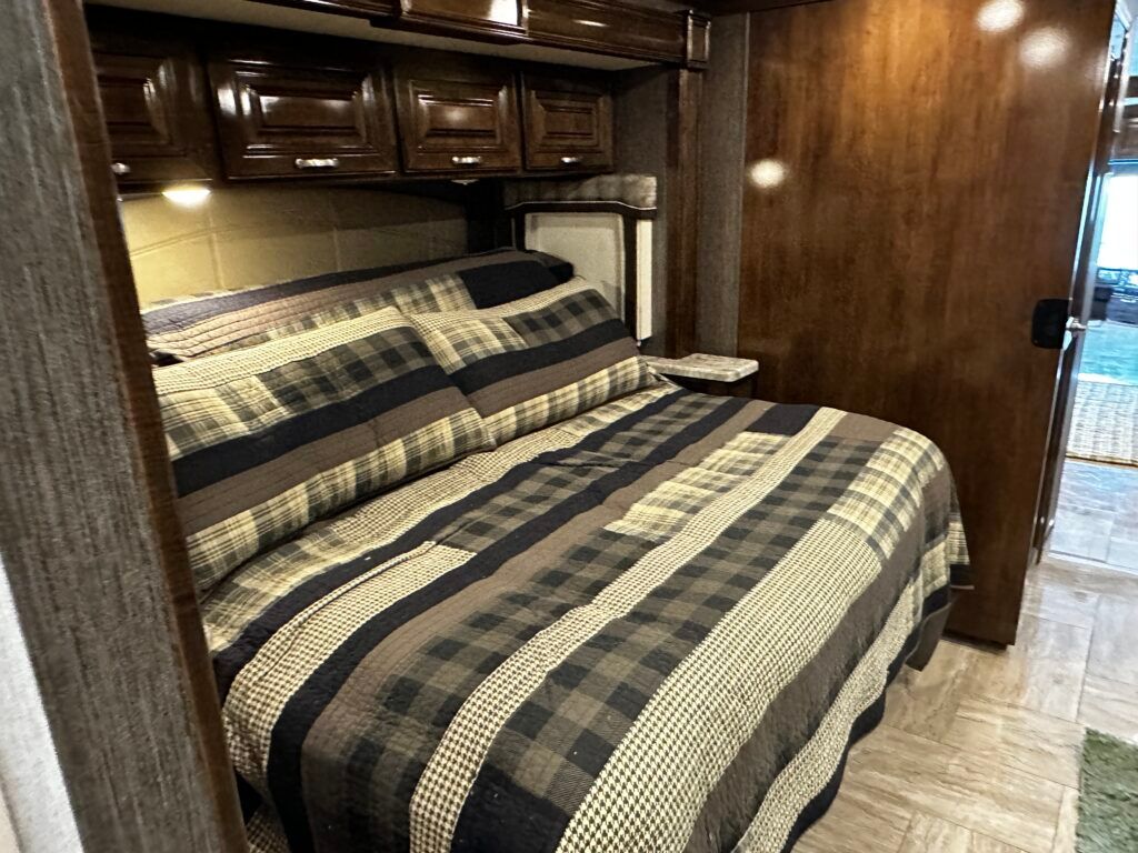 A bed with a striped comforter and pillows in a rv.