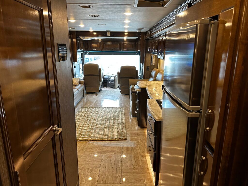 The inside of a rv with a refrigerator and a living room.