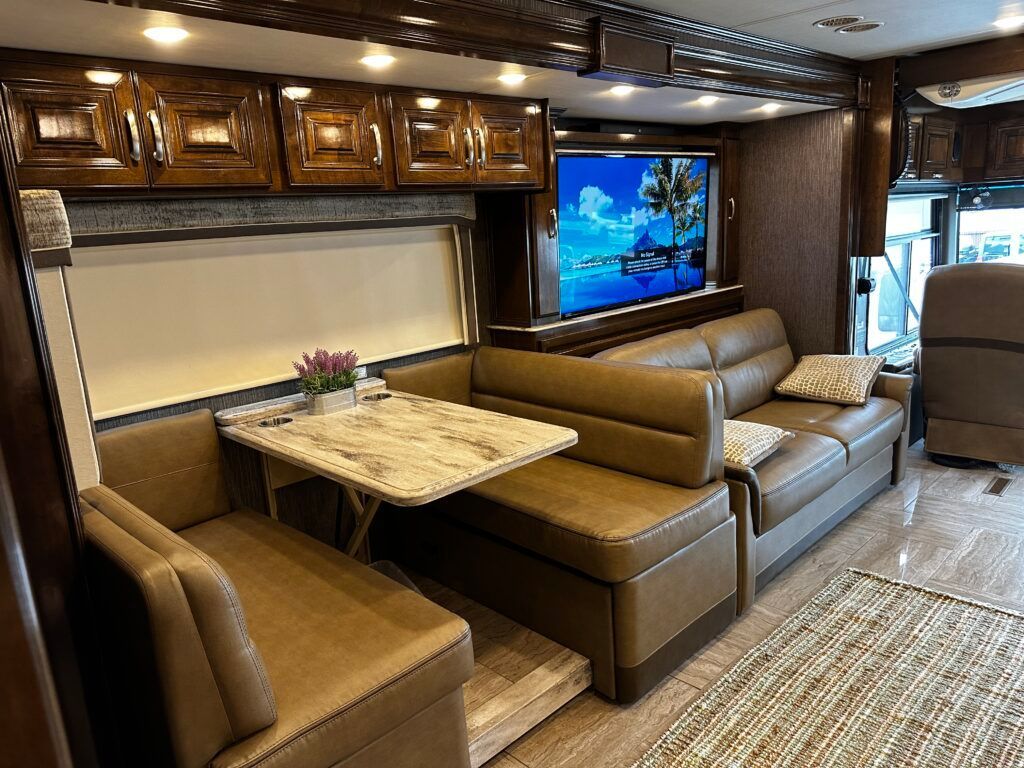 A living room in a rv with a couch , table and television.