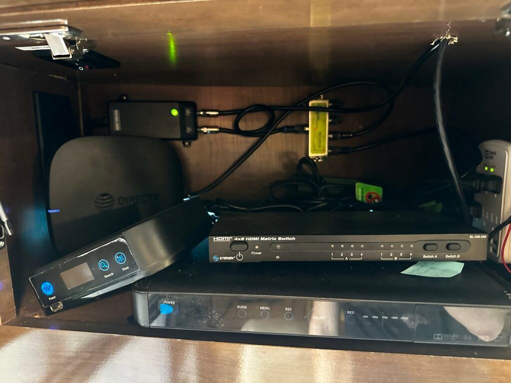 A variety of electronic devices are sitting inside of a cabinet.