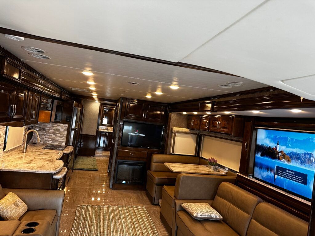 A living room in a rv with a couch , table and television.