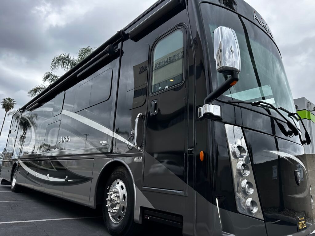A large black rv is parked in a parking lot.