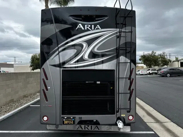 The back of a large aria rv is parked in a parking lot.