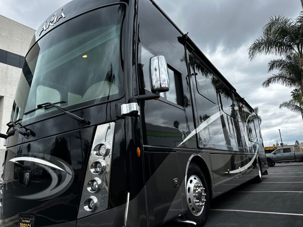 A large black rv is parked in a parking lot.