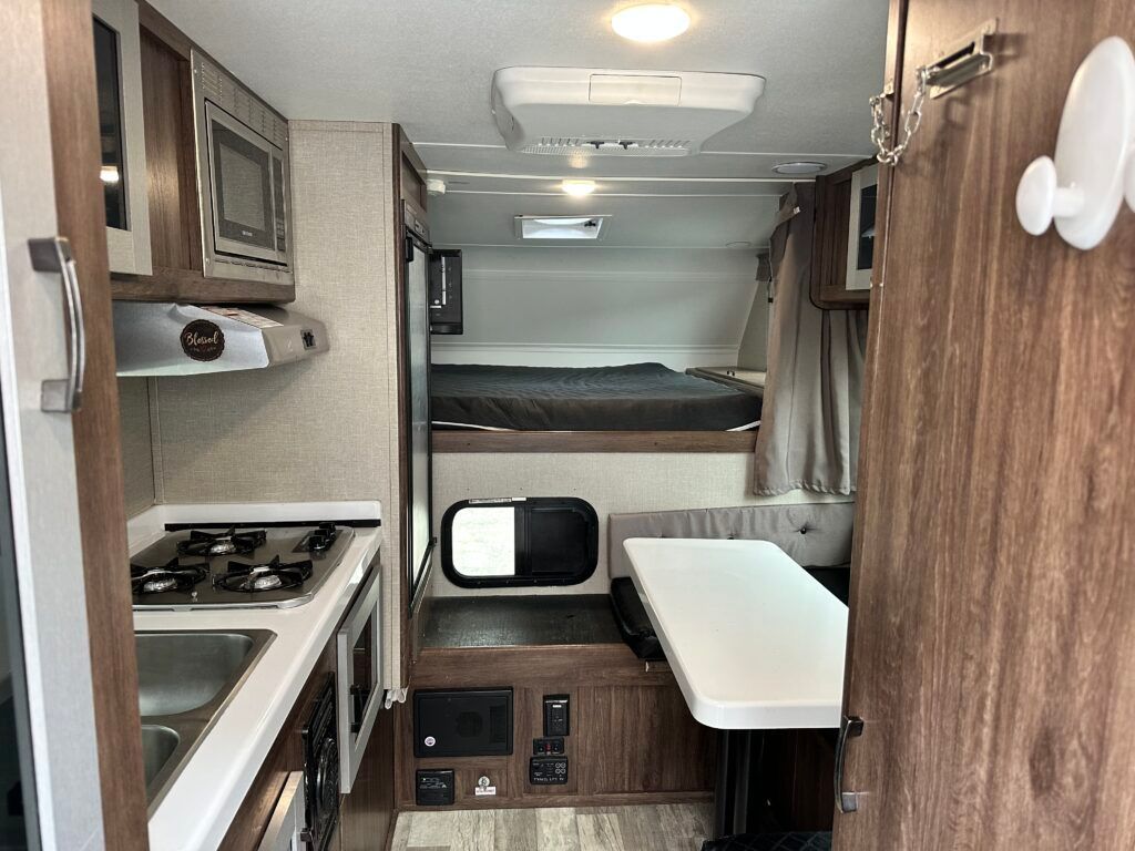 The inside of a rv with a stove , sink , and table.