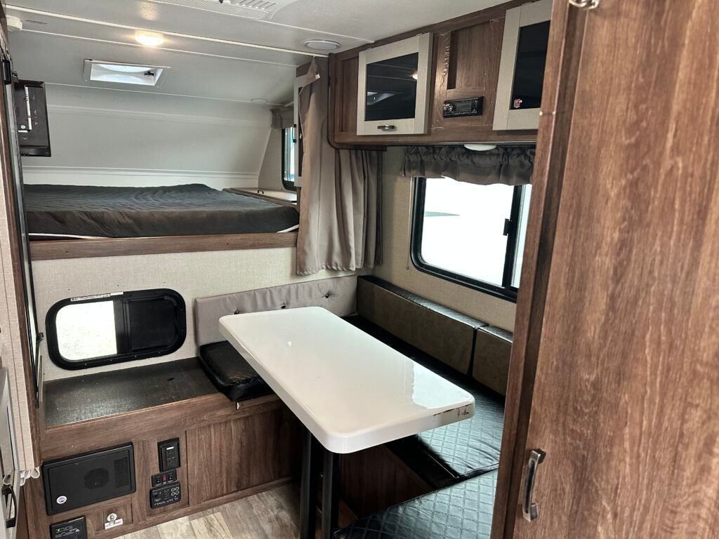 A rv with a table and a bed in it.