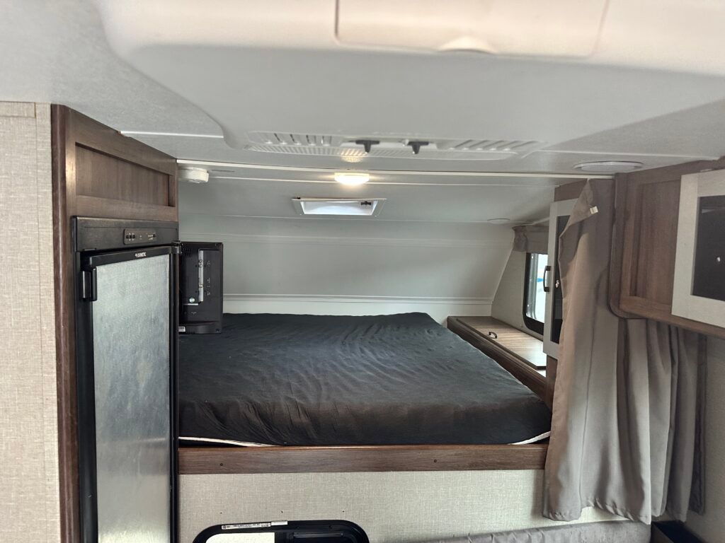 There is a bed in the back of a camper.