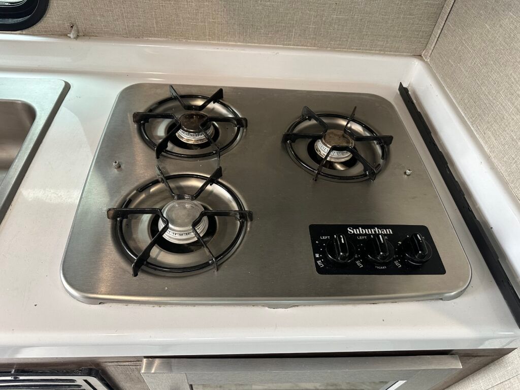 A stainless steel gas stove with three burners in a kitchen.
