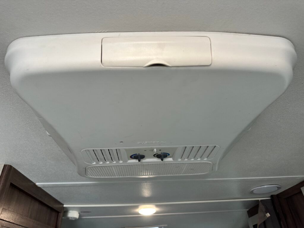 A white ceiling fan is hanging from the ceiling of a vehicle.