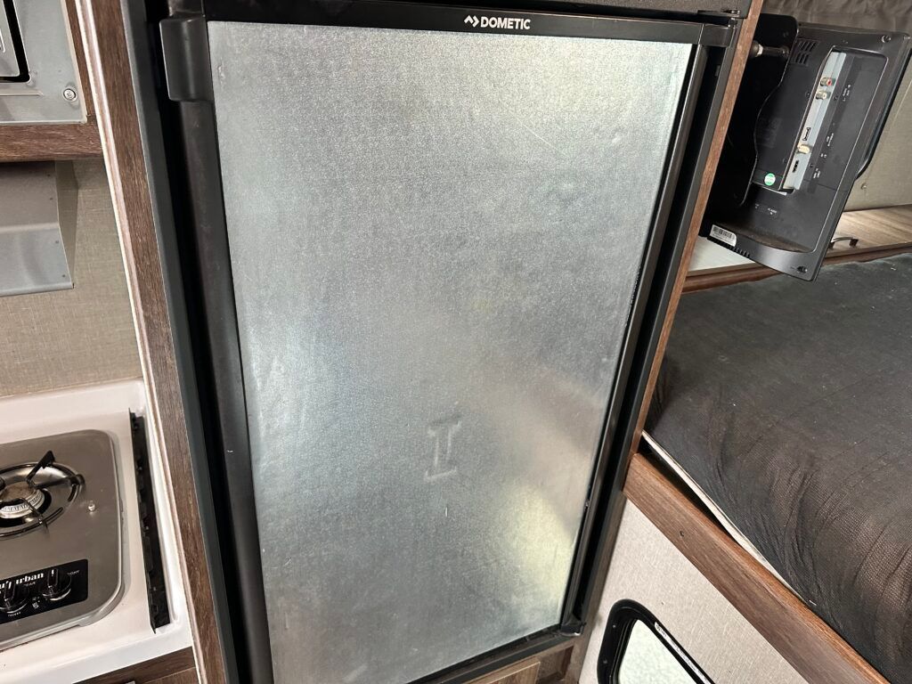 A stainless steel refrigerator is sitting in a camper.