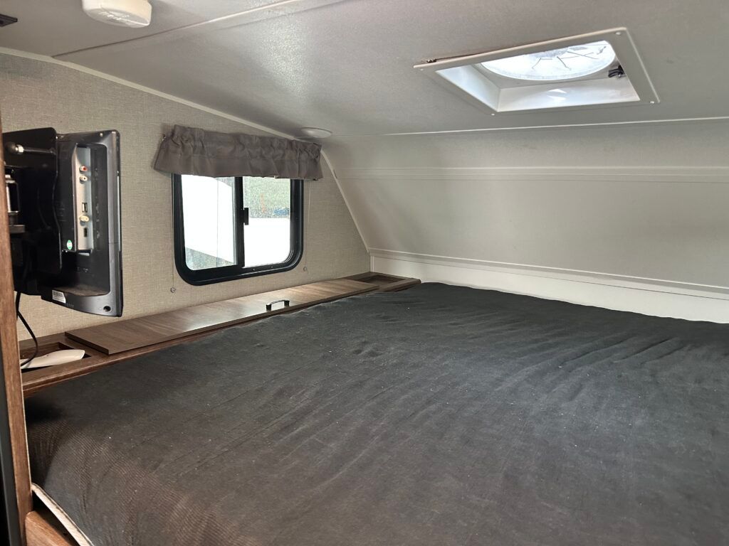 There is a bed in the middle of the room in a trailer.