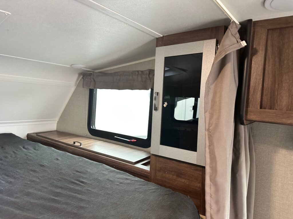 A bedroom in a camper with a bed and a window.