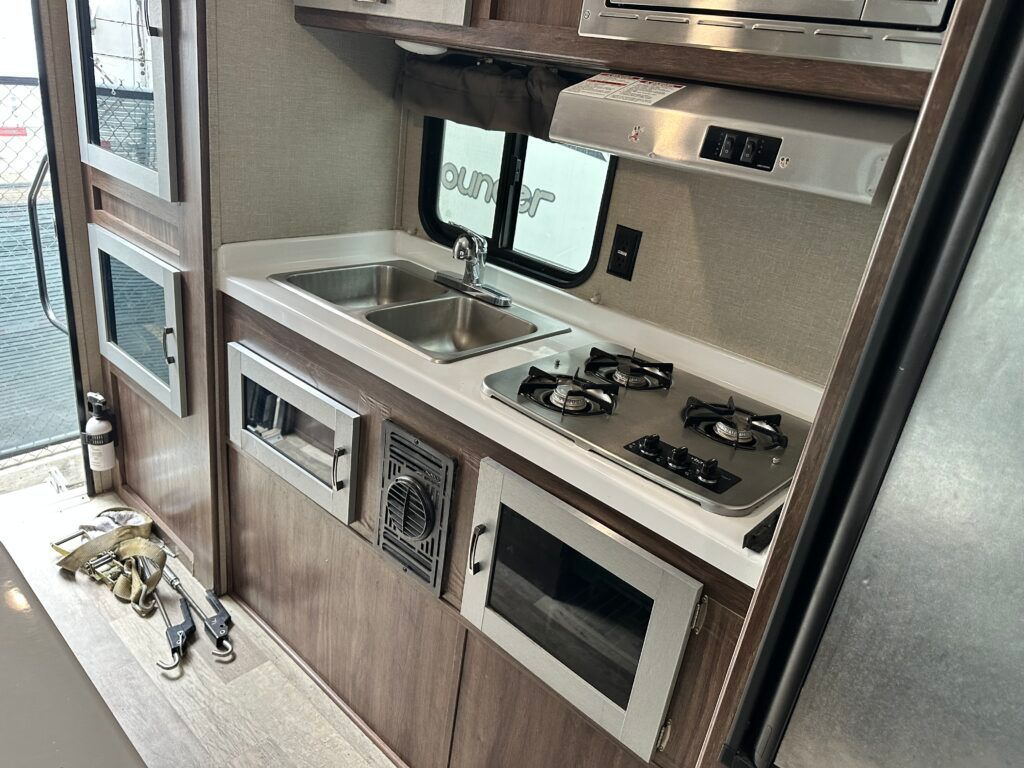 A kitchen with a sink , stove , microwave and refrigerator.