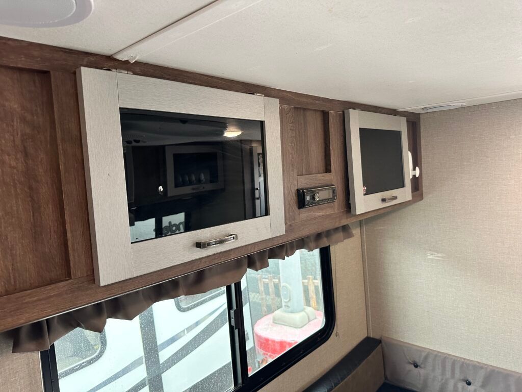 A rv with two televisions mounted to the ceiling.