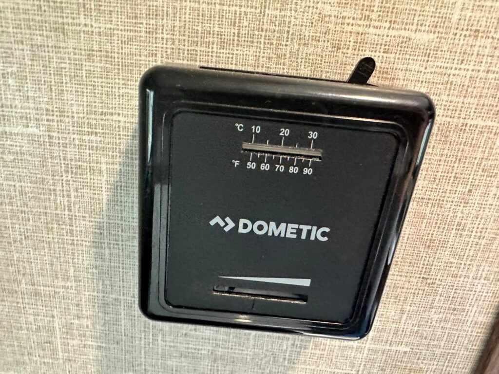 A dometic thermostat is hanging on a wall.