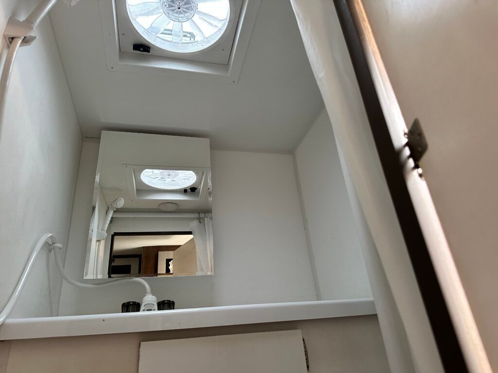 A bathroom with a skylight and a fan on the ceiling.