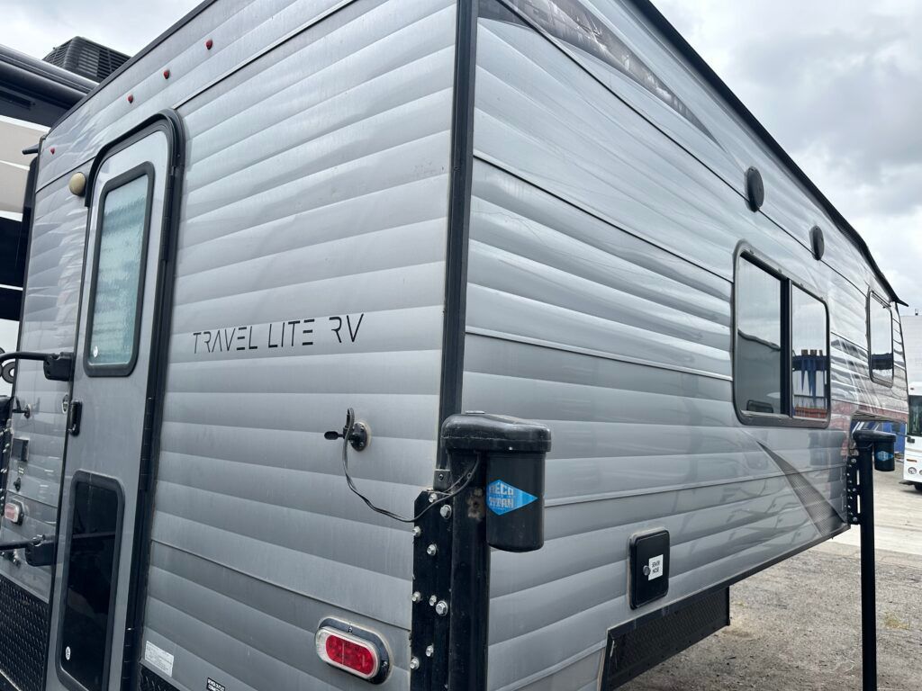 A silver travel trailer is parked in a parking lot.