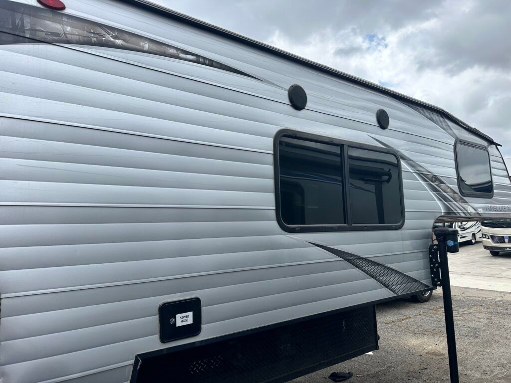 A silver trailer is parked in a parking lot.