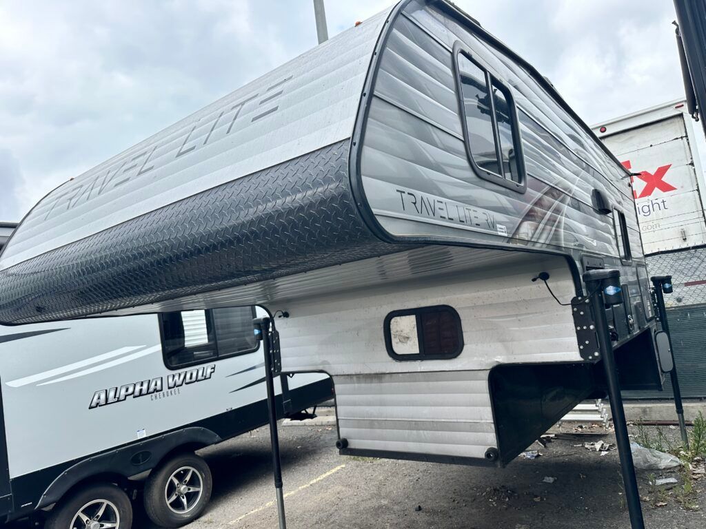 A trailer is parked in a parking lot next to a truck.