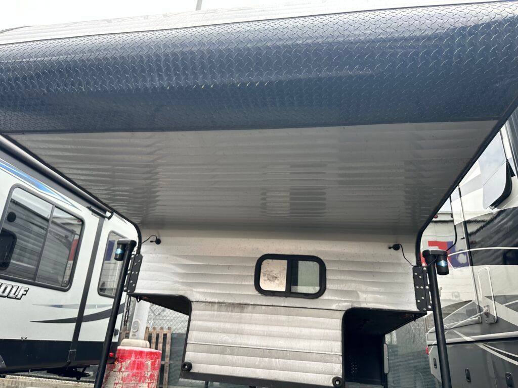 A trailer with a canopy on top of it is parked next to a trailer.